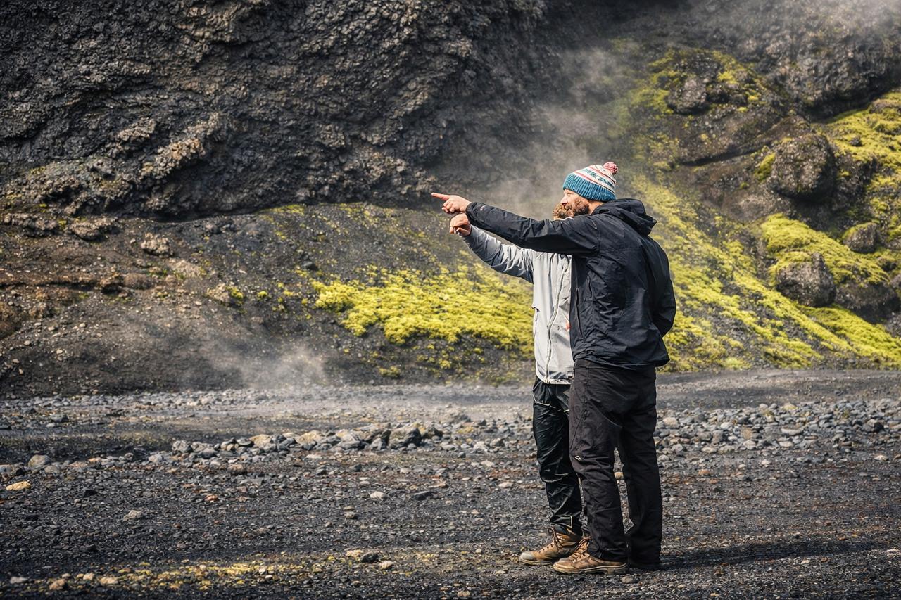Tveir leiðsögumenn í rjúkandi eldfjalladal, annar þeirra vísar í fjarska